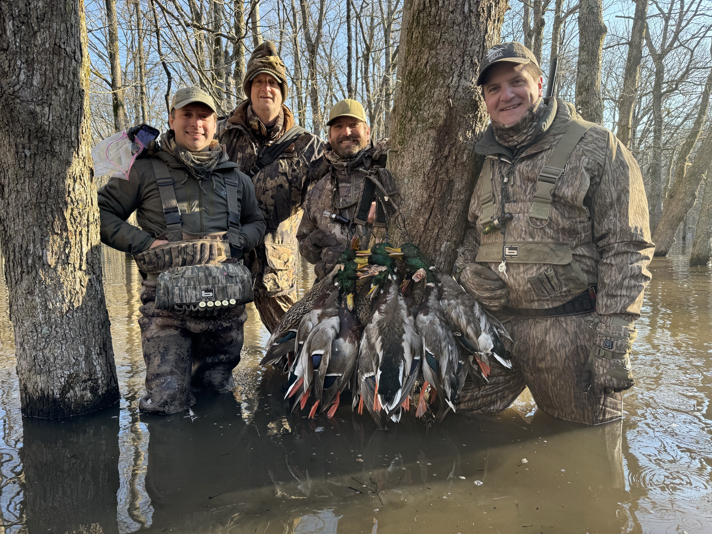 Four hunters in the flooded timber with the morning’s strap of mallards.