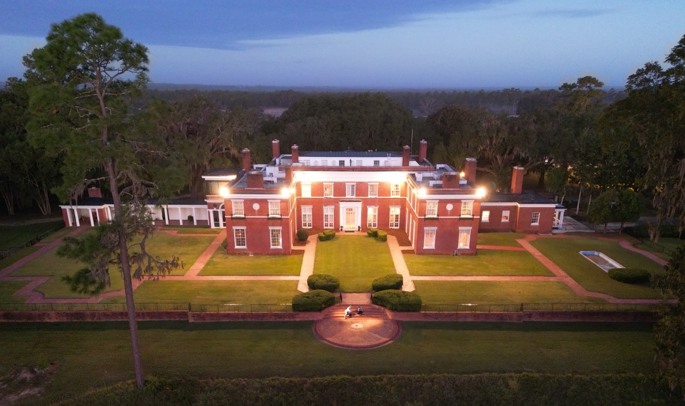Livingston Place Manor lit at dusk, from above the front lawn.