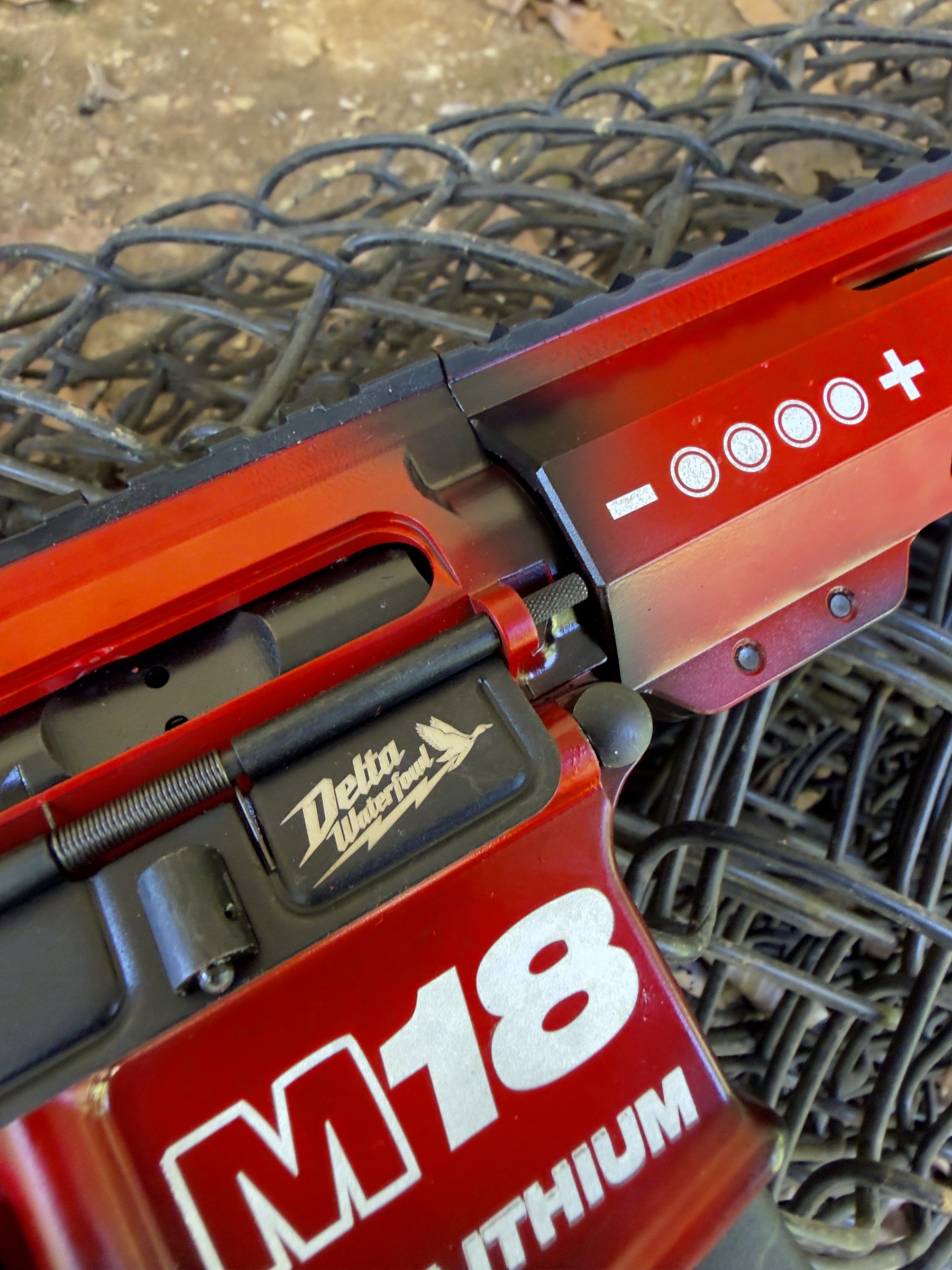 The Delta Waterfowl mark on the rifle's dust cover, beside the battery gauge on the handguard.