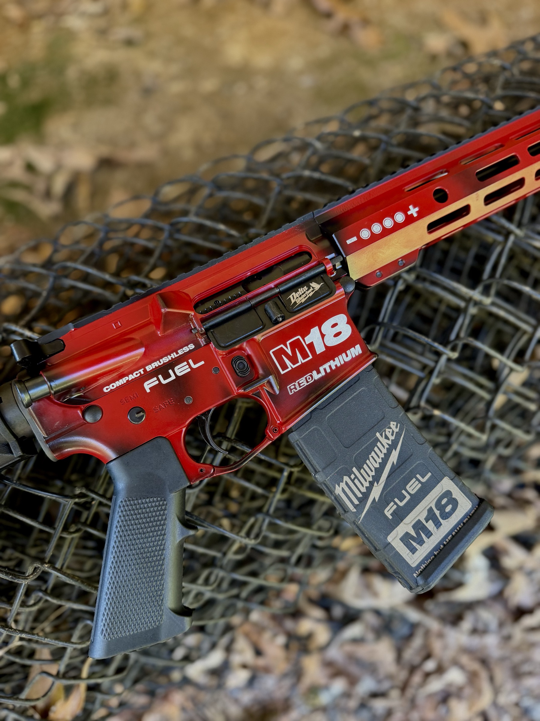 The Tool Daddy rifle's lower receiver in Milwaukee red, marked M18 REDLITHIUM and FUEL, with a Milwaukee M18 magazine.