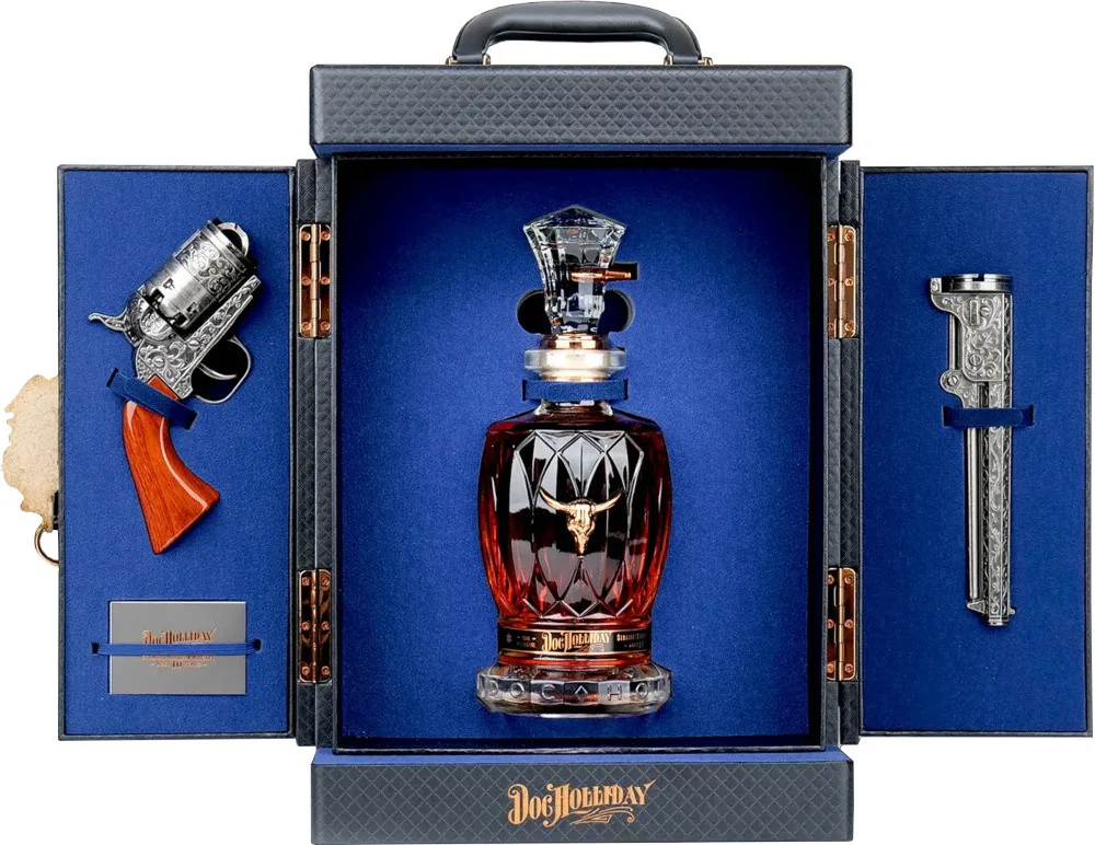 The gift case open, the cut-crystal decanter standing between an engraved revolver grip and its barrel.